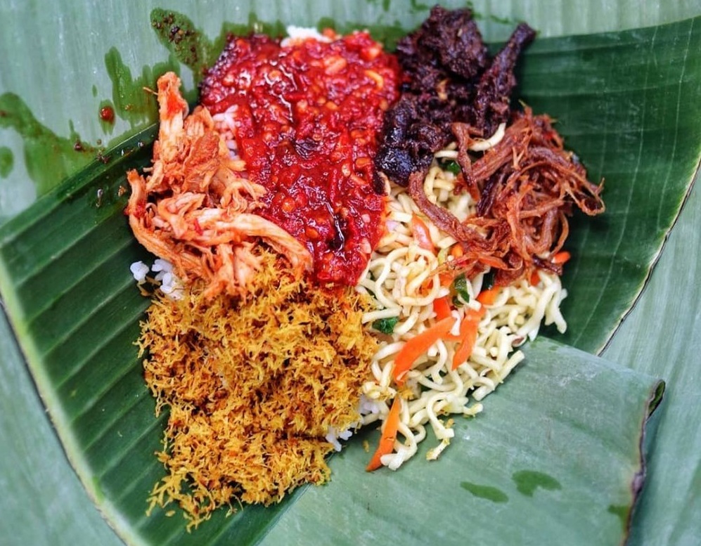 jinggo rice is served in a banana leaf wrapper with side dishes and condiment